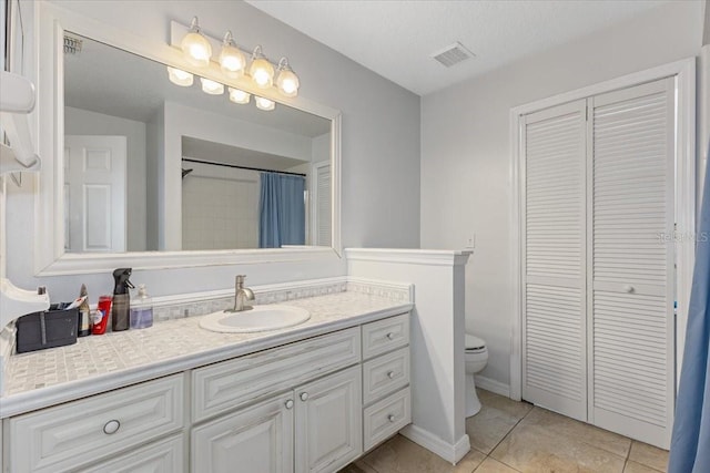 bathroom with tile patterned flooring, vanity, a textured ceiling, and toilet