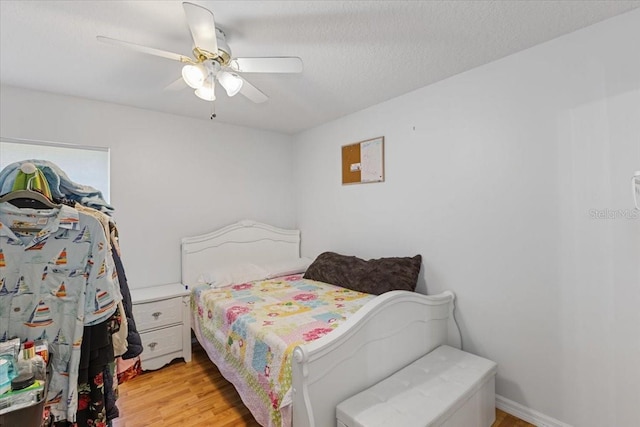 bedroom featuring ceiling fan, light hardwood / wood-style flooring, and a textured ceiling