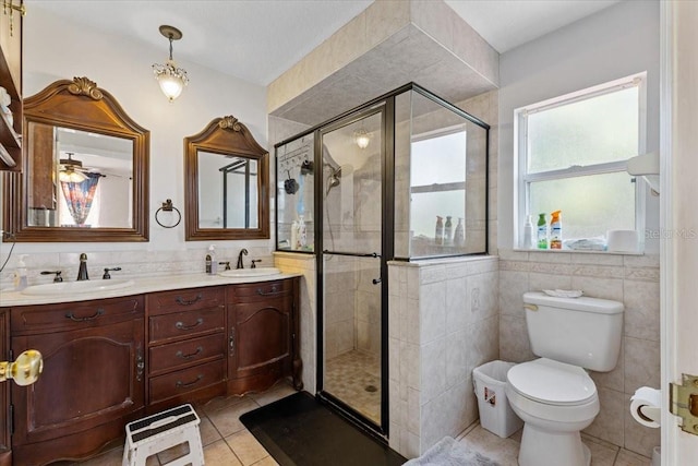 bathroom featuring tile patterned floors, toilet, an enclosed shower, tile walls, and vanity