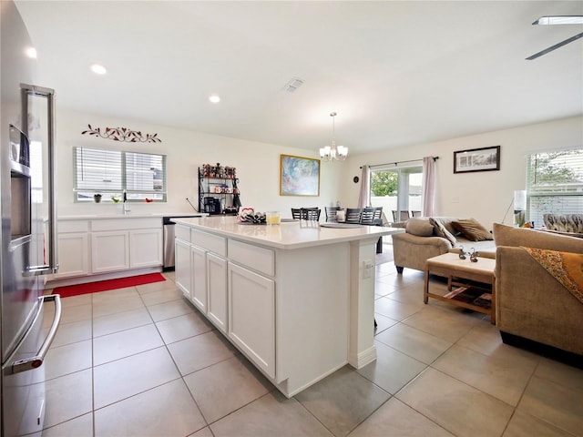 kitchen with a center island, pendant lighting, an inviting chandelier, white cabinetry, and light tile patterned floors