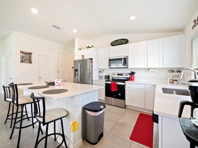 kitchen featuring light tile patterned floors, stainless steel appliances, white cabinetry, and a center island