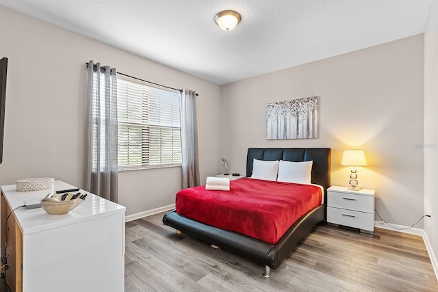 bedroom with a textured ceiling and light hardwood / wood-style floors