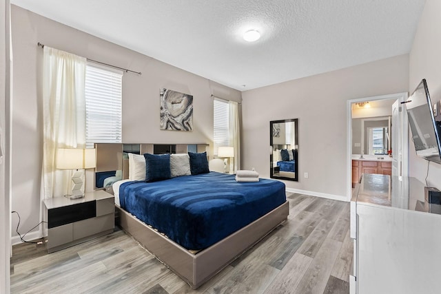 bedroom featuring light hardwood / wood-style floors, connected bathroom, and a textured ceiling