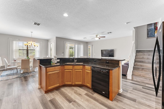 kitchen featuring hanging light fixtures, black appliances, light wood-type flooring, and an island with sink