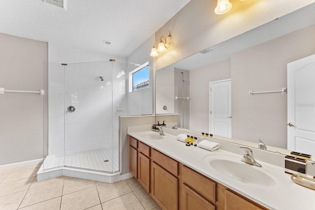 bathroom with a shower with door, a textured ceiling, tile patterned floors, and double sink vanity