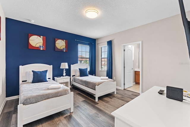 bedroom with wood-type flooring, connected bathroom, and a textured ceiling