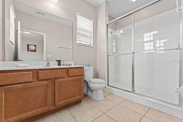 bathroom with a shower with door, vanity, toilet, and tile patterned floors