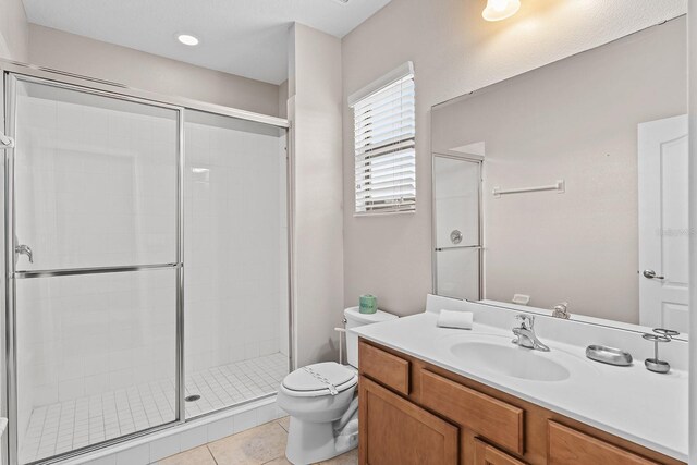 bathroom with tile patterned flooring, walk in shower, toilet, and vanity