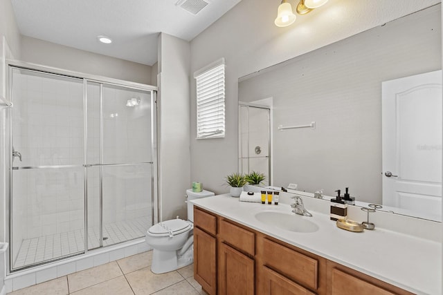 bathroom with tile patterned floors, toilet, vanity, and an enclosed shower