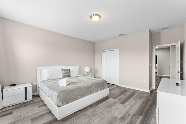 bedroom with hardwood / wood-style floors, a closet, and a textured ceiling