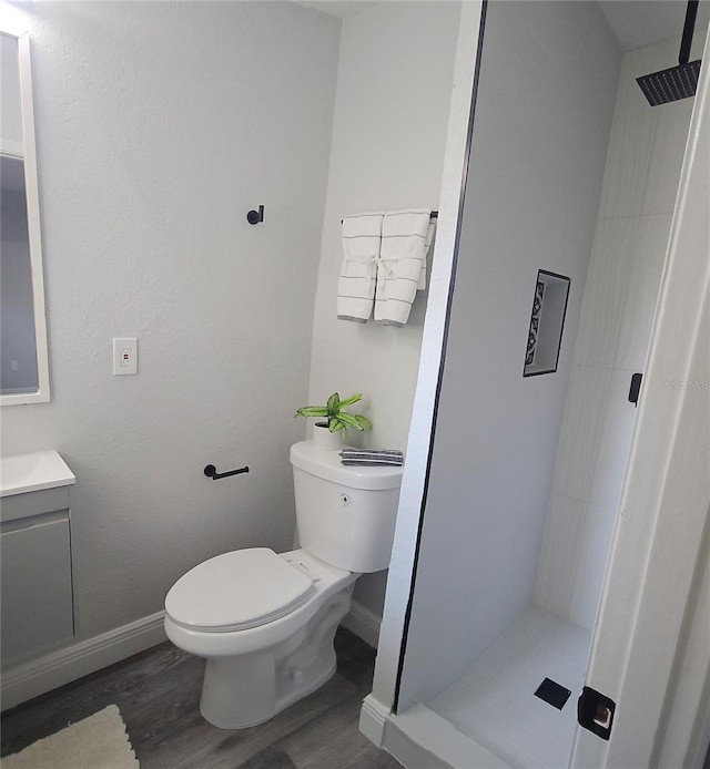 bathroom featuring vanity, a tile shower, hardwood / wood-style flooring, and toilet