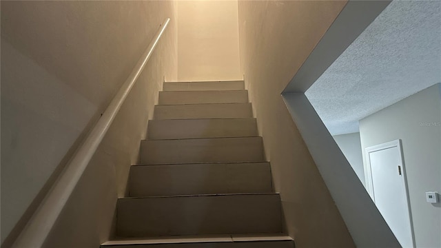 stairs featuring a textured ceiling