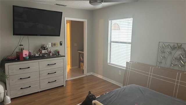 bedroom with ceiling fan, a textured ceiling, and dark hardwood / wood-style floors