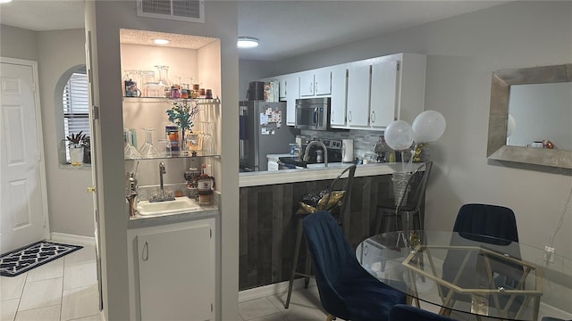 kitchen featuring white cabinetry, appliances with stainless steel finishes, light tile patterned floors, and sink