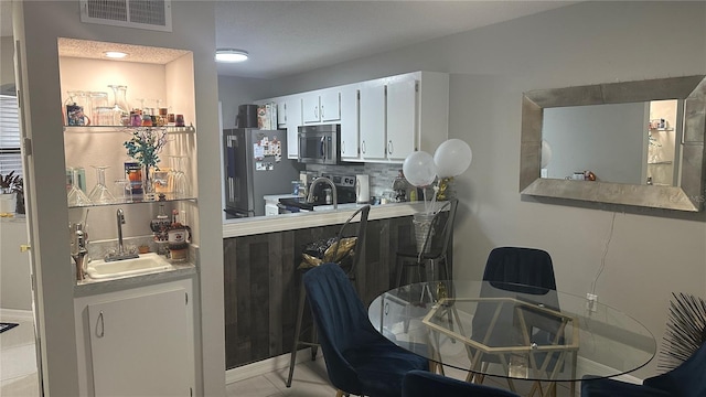 kitchen featuring a textured ceiling, sink, white cabinetry, backsplash, and appliances with stainless steel finishes