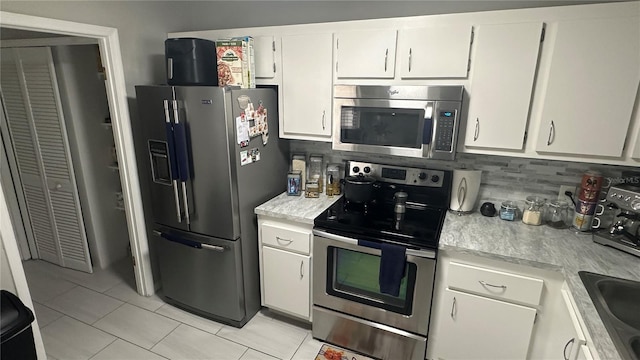 kitchen featuring appliances with stainless steel finishes, backsplash, white cabinetry, and light tile patterned floors