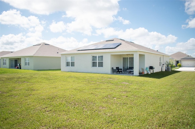 rear view of house with a yard and solar panels