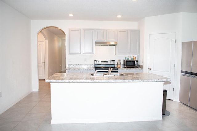 kitchen featuring sink, light stone countertops, a center island with sink, appliances with stainless steel finishes, and light tile patterned floors