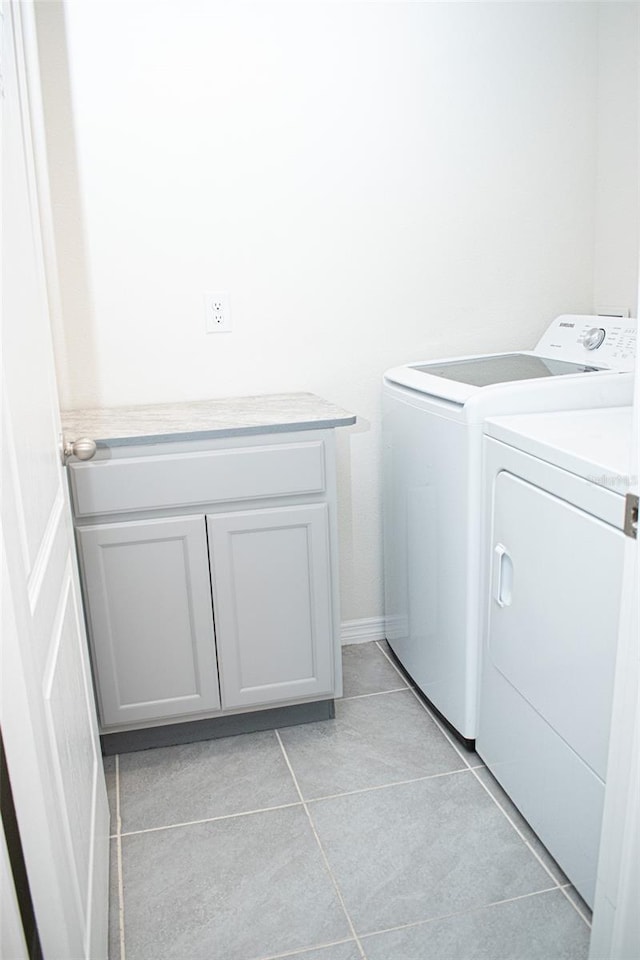 clothes washing area with cabinets, separate washer and dryer, and light tile patterned floors