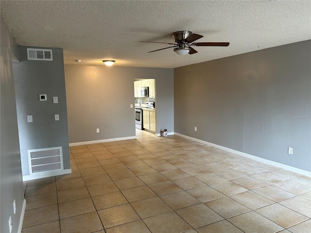 interior space featuring ceiling fan, light tile patterned floors, and a textured ceiling