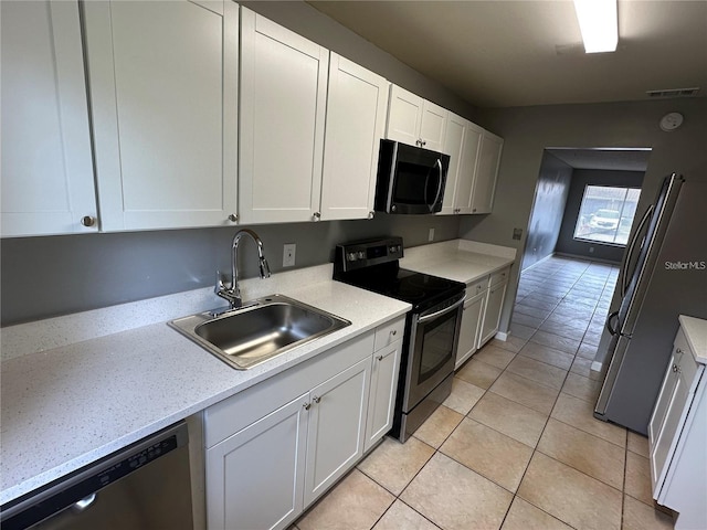 kitchen featuring white cabinetry, sink, light tile patterned floors, and stainless steel appliances