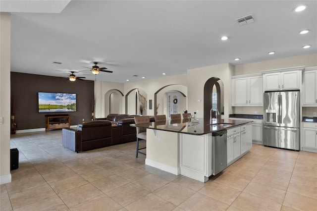 kitchen featuring stainless steel appliances, sink, white cabinets, and an island with sink