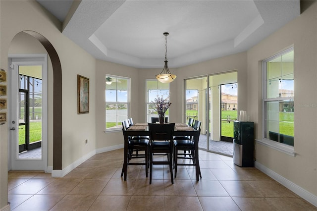 tiled dining space with a raised ceiling