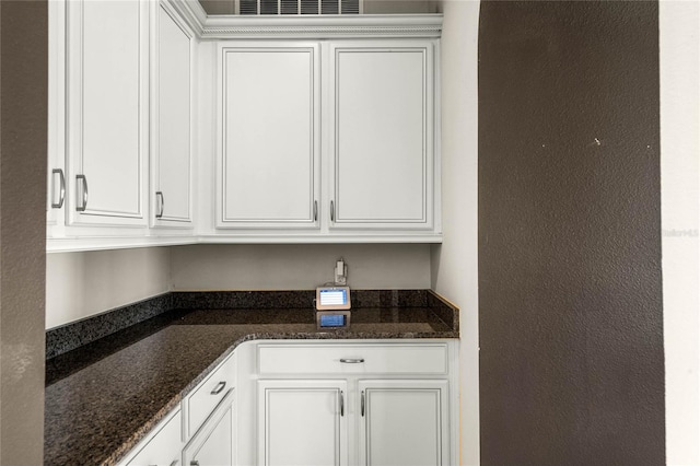 interior space with white cabinetry and dark stone counters