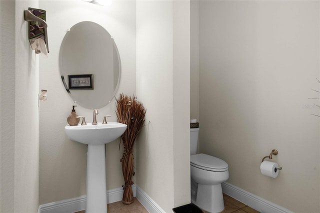 bathroom with toilet, tile patterned flooring, and sink