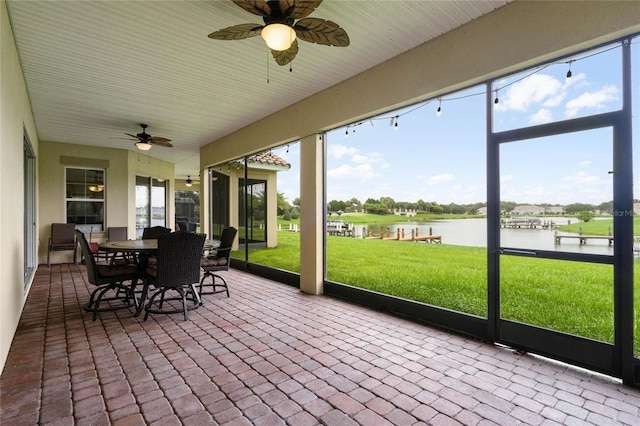 unfurnished sunroom featuring ceiling fan and a water view