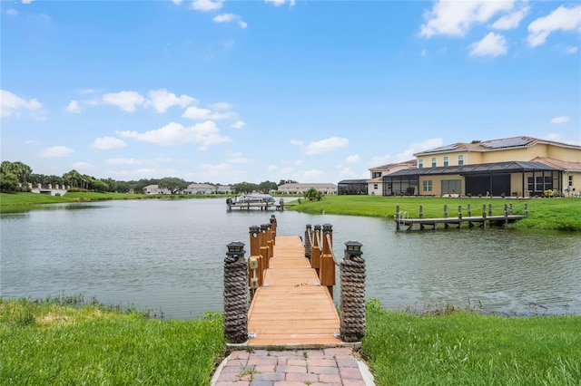 view of dock with a lanai, a water view, and a lawn