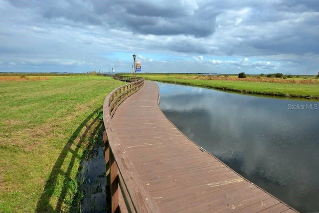 view of dock with a water view and a lawn