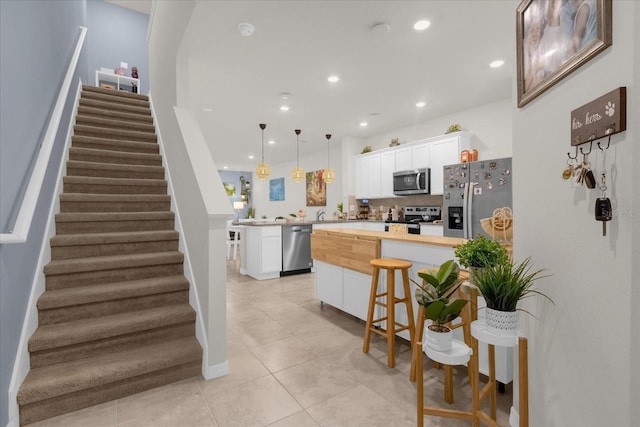 kitchen featuring recessed lighting, stainless steel appliances, a peninsula, white cabinets, and decorative light fixtures