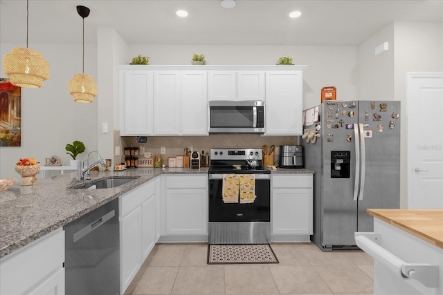 kitchen with appliances with stainless steel finishes, white cabinets, a sink, and light tile patterned floors