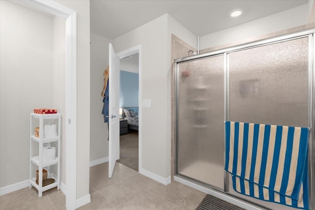 ensuite bathroom with ensuite bathroom, a stall shower, baseboards, and tile patterned floors