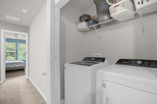 washroom featuring washer and clothes dryer, visible vents, light colored carpet, laundry area, and baseboards