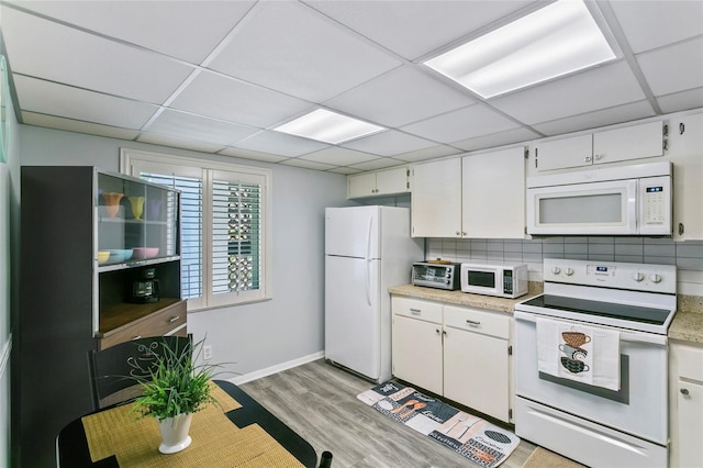 kitchen featuring tasteful backsplash, a paneled ceiling, light wood-type flooring, white appliances, and white cabinets