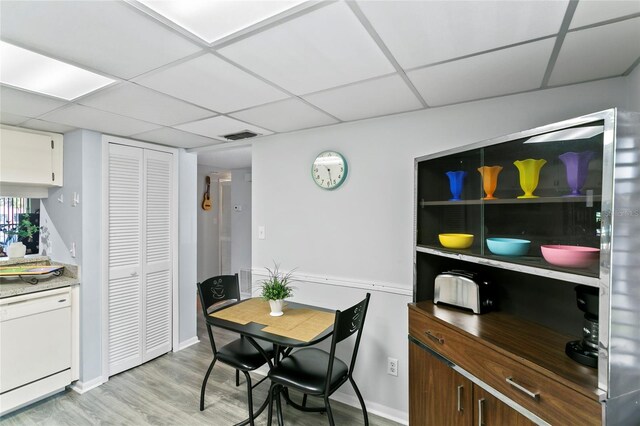 dining area featuring a drop ceiling and light hardwood / wood-style floors