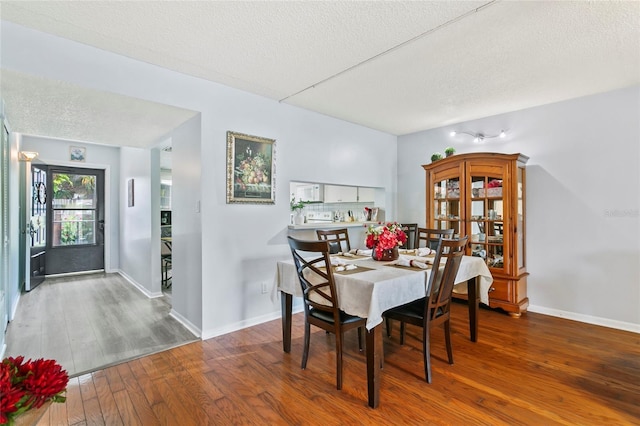 dining area featuring wood-type flooring and a textured ceiling