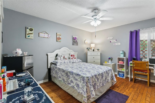 bedroom featuring dark hardwood / wood-style flooring, ceiling fan, stainless steel refrigerator, and a textured ceiling