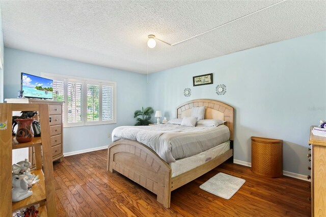 bedroom with dark hardwood / wood-style floors and a textured ceiling