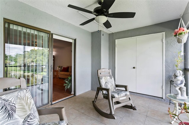 sitting room featuring ceiling fan, a textured ceiling, and light tile patterned flooring