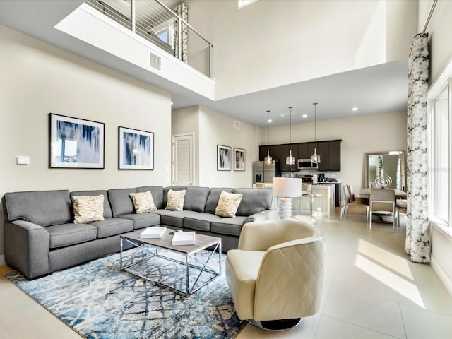 living room with a wealth of natural light, a high ceiling, and tile patterned floors