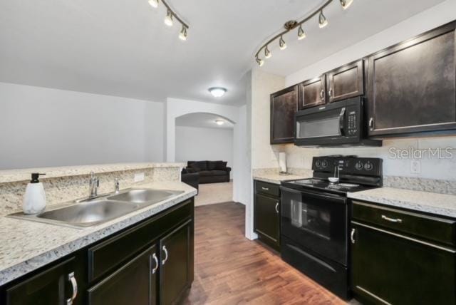 kitchen featuring sink, dark brown cabinetry, black appliances, light stone countertops, and dark wood-type flooring