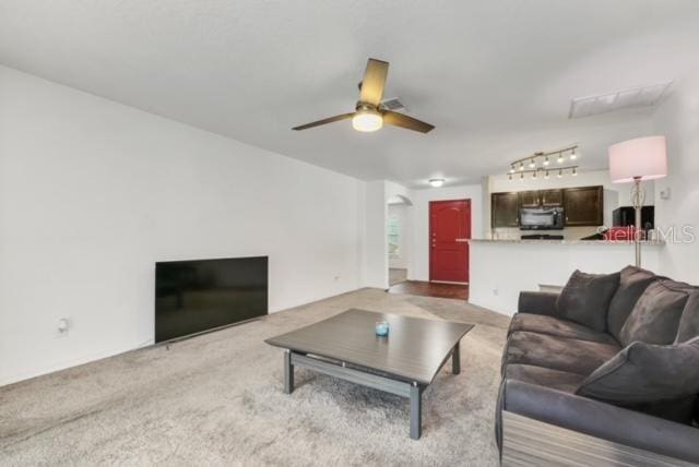 carpeted living room featuring track lighting and ceiling fan