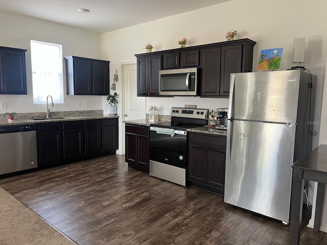 kitchen featuring light stone countertops, appliances with stainless steel finishes, sink, and dark hardwood / wood-style flooring