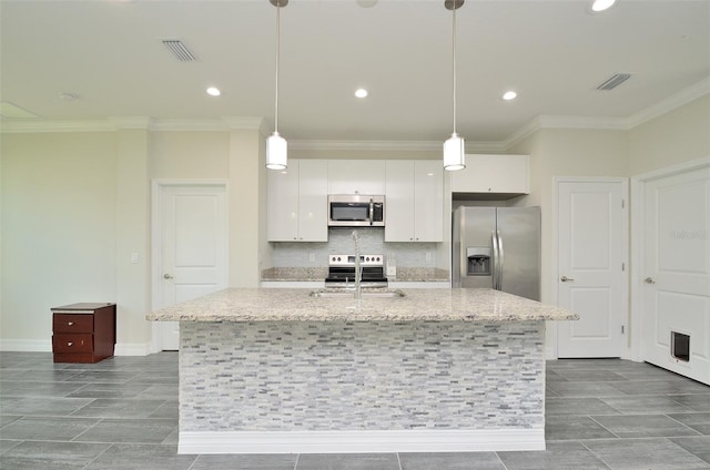 kitchen featuring white cabinets, appliances with stainless steel finishes, decorative light fixtures, and a center island with sink