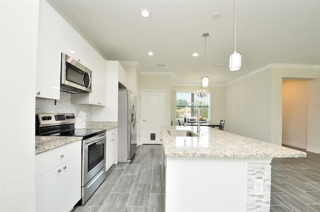 kitchen featuring white cabinetry, a center island with sink, hanging light fixtures, crown molding, and stainless steel appliances