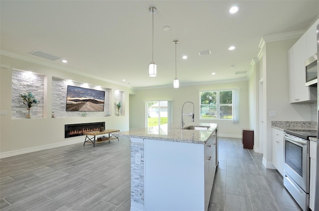 kitchen featuring white cabinetry, sink, a kitchen island with sink, white electric stove, and decorative light fixtures