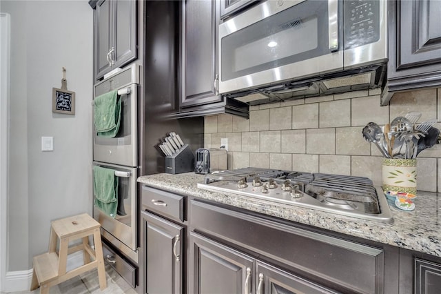 12151 Alder Branch Loop, Orlando, FL 32824 - kitchen featuring appliances with stainless steel finishes, decorative backsplash, light stone countertops, and baseboards